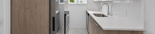 A modern kitchen with a refrigerator, sink, and cabinets.
