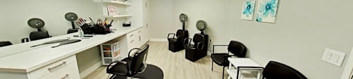 A room with a white desk and black chairs.