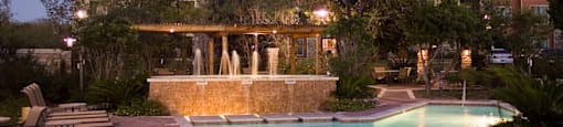 a large swimming pool with a waterfall in front of a large house