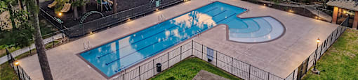 A swimming pool surrounded by a fence and trees.