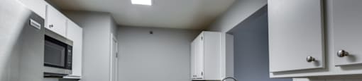 Apartment kitchen with stainless steel appliances and white cabinets.