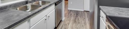 Apartment kitchen with a stainless steel refrigerator and a double sink.