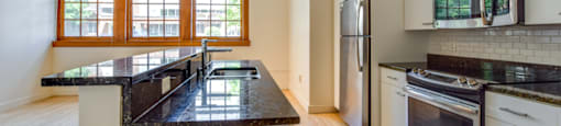 Historic Apartment kitchen with a black countertop and white cabinets.