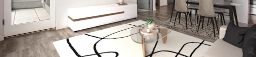 a living room with a white rug and a kitchen with a table and chairs