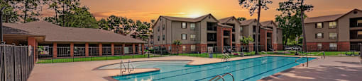 A sunset view of a swimming pool surrounded by apartment buildings.
