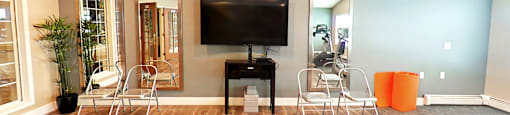 A living room with a wooden floor and a television mounted on the wall.