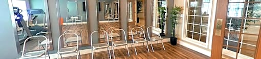 A room with a row of chairs and mirrors on the wall.