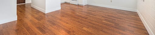 an empty living room and kitchen with wood flooring