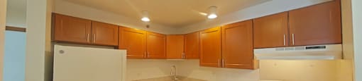 A kitchen with white appliances and brown cabinets.