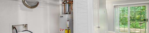 a gas boiler in a garage with a door to the outside