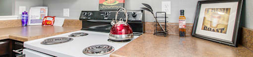 a kitchen with a stove top oven next to a counter top with a kettle on it