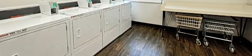 A laundry room with a row of washing machines and a clock on the wall.