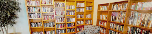 A living room with a couch, a chair, a coffee table, and a bookshelf filled with books.