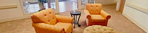 A living room with two chairs and a footstool.