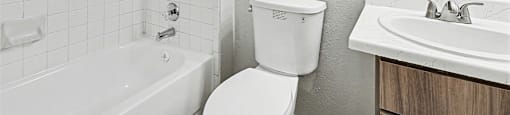 A white toilet sits next to a white sink in a bathroom.