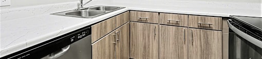 A kitchen with wooden cabinets and a stainless steel dishwasher.