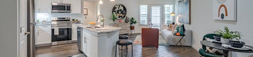 A modern kitchen with a white island and bar stools.