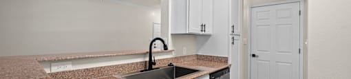A kitchen with white cabinets and a granite countertop.