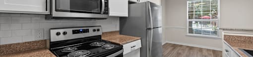 A kitchen with a stove, microwave, and refrigerator.