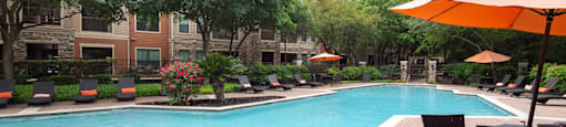 a pool with lounge chairs and umbrellas at the oxford at the boulevard apartments