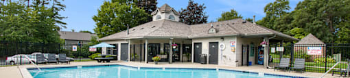 a swimming pool with a clubhouse in the background