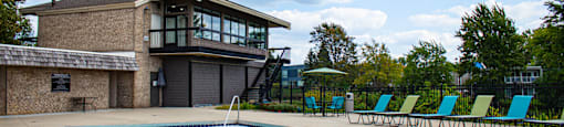 a swimming pool in front of a building with green chairs