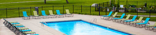a swimming pool with chairs and a table with an umbrella
