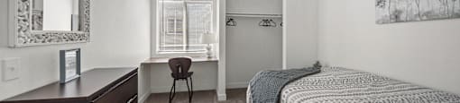 A bedroom with a bed, desk, and chair.