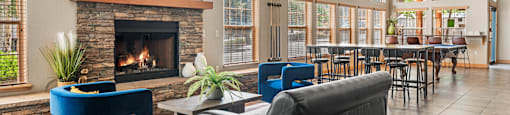 A living room with a stone fireplace and blue chairs.