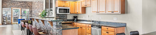 A kitchen with a bar area and wooden cabinets.