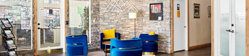 A stone wall with a staircase on the left and a yellow chair in the middle of the room.