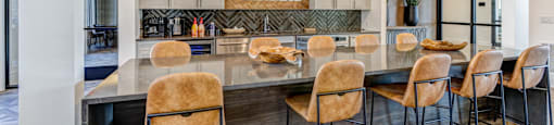 A modern kitchen with a large island and chairs.