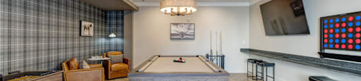 A room with a pool table and a television on the wall.