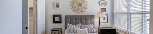 A bedroom with a bed, a ceiling fan, and a wall decoration.