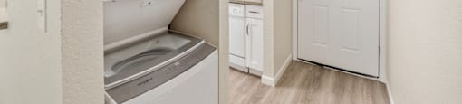 a renovated kitchen with white cabinets and a white door and a washer and dry