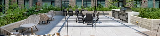 Outdoor patio with swings, lounge chairs, and grills at Arrowwood Apartments, North Bethesda