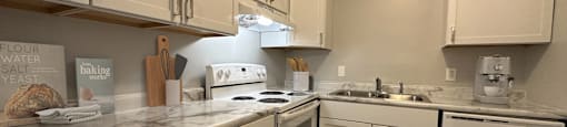 a kitchen with white cabinets and a white rug