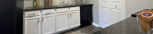 a kitchen with white cabinets and a black counter top
