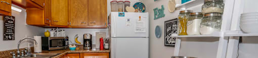 A kitchen with a white fridge and wooden cabinets.
