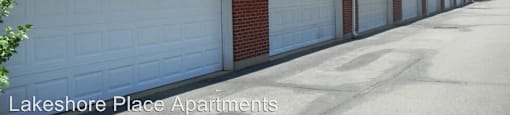 A row of garage doors in front of a building with the text Lakeshore Place Apartments.