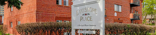 A sign for a place called "Lakeshore Place" stands in front of a red brick building.