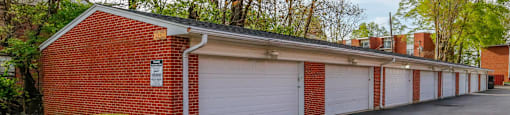 A red brick building with white garage doors in front of a tree.