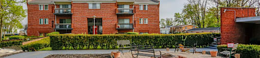 A red brick building with a patio and a fire pit in front.