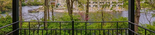 A view of a river through a fence with trees in the foreground.