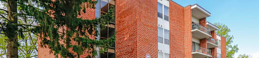 A red brick apartment building with a tree in front.