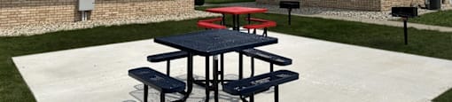 a picnic area outside of a building with two picnic tables
