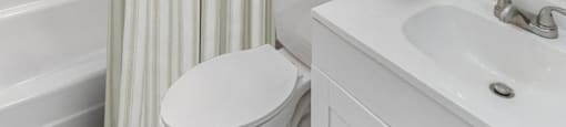A white bathroom with a toilet, sink, and shower.