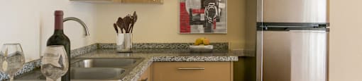 A kitchen with a granite counter top and a refrigerator.
