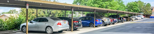 A parking lot with cars parked under a covered walkway.