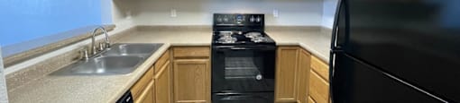 A kitchen with black appliances and wooden cabinets.
